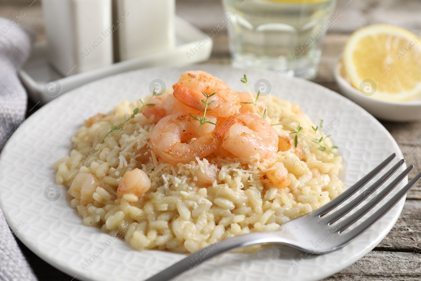 Photo of Delicious risotto with shrimps and cheese on wooden table, closeup