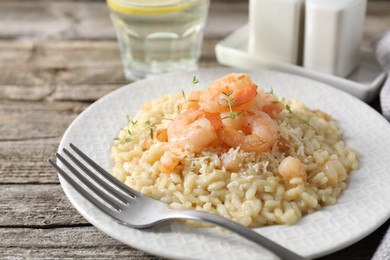 Photo of Delicious risotto with shrimps and cheese on wooden table, closeup