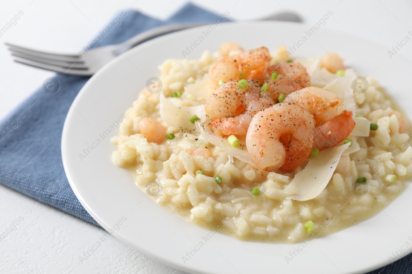 Photo of Delicious risotto with shrimps and cheese on white table, closeup