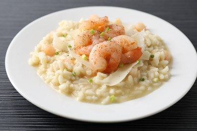 Photo of Delicious risotto with shrimps and cheese on black table, closeup