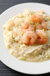 Photo of Delicious risotto with shrimps and cheese on black table, closeup