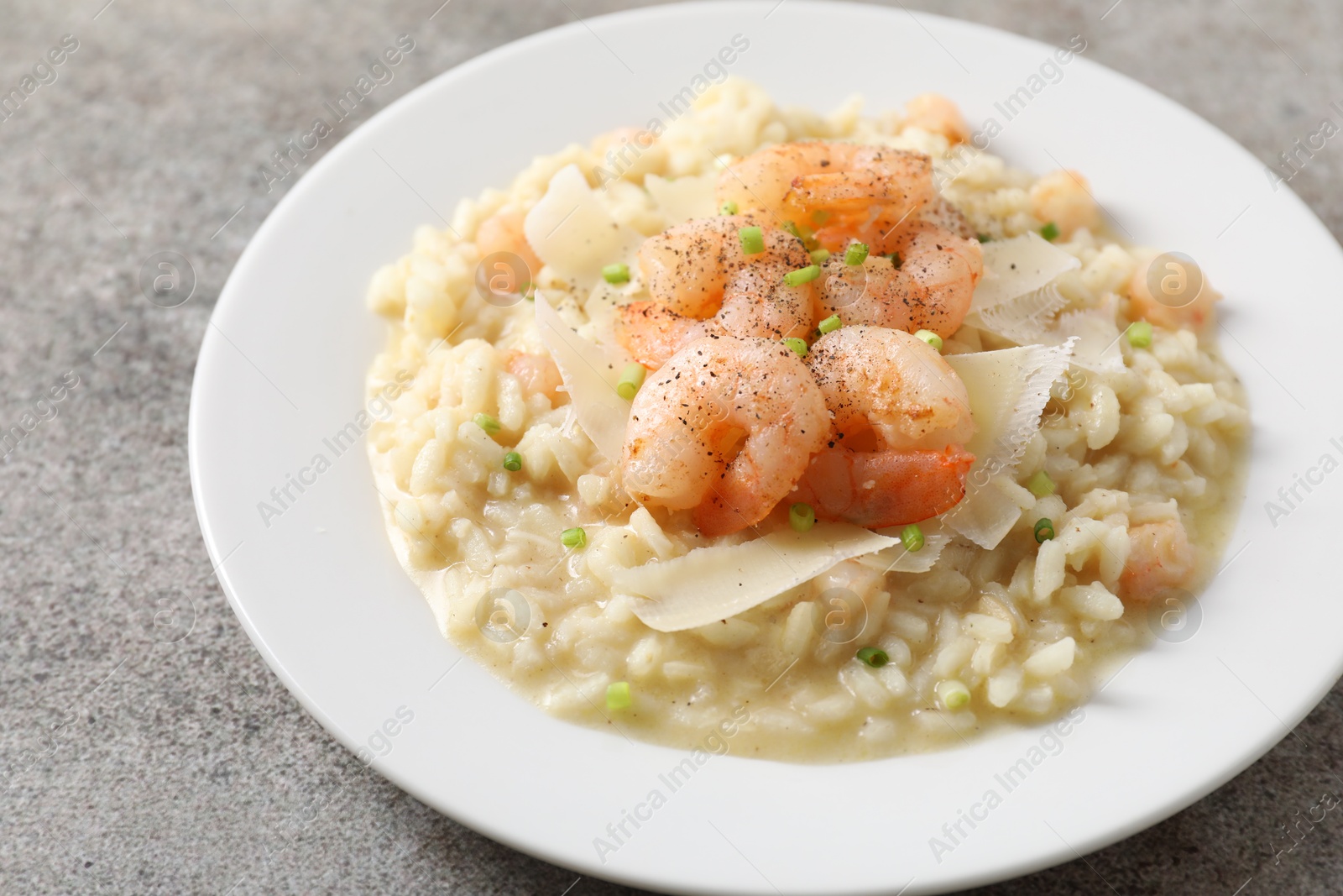 Photo of Delicious risotto with shrimps and cheese on grey table, closeup