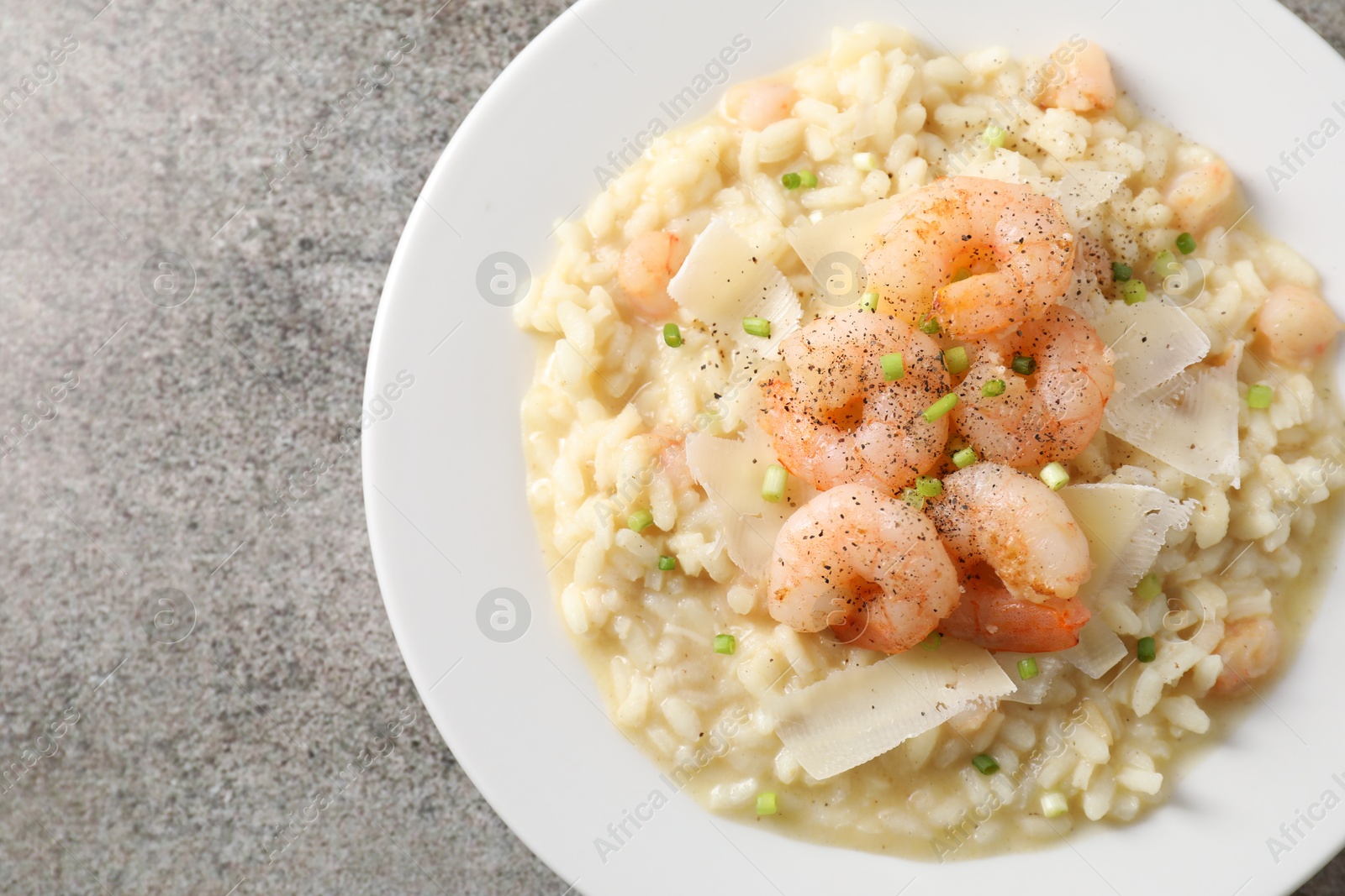 Photo of Delicious risotto with shrimps and cheese on grey table, top view