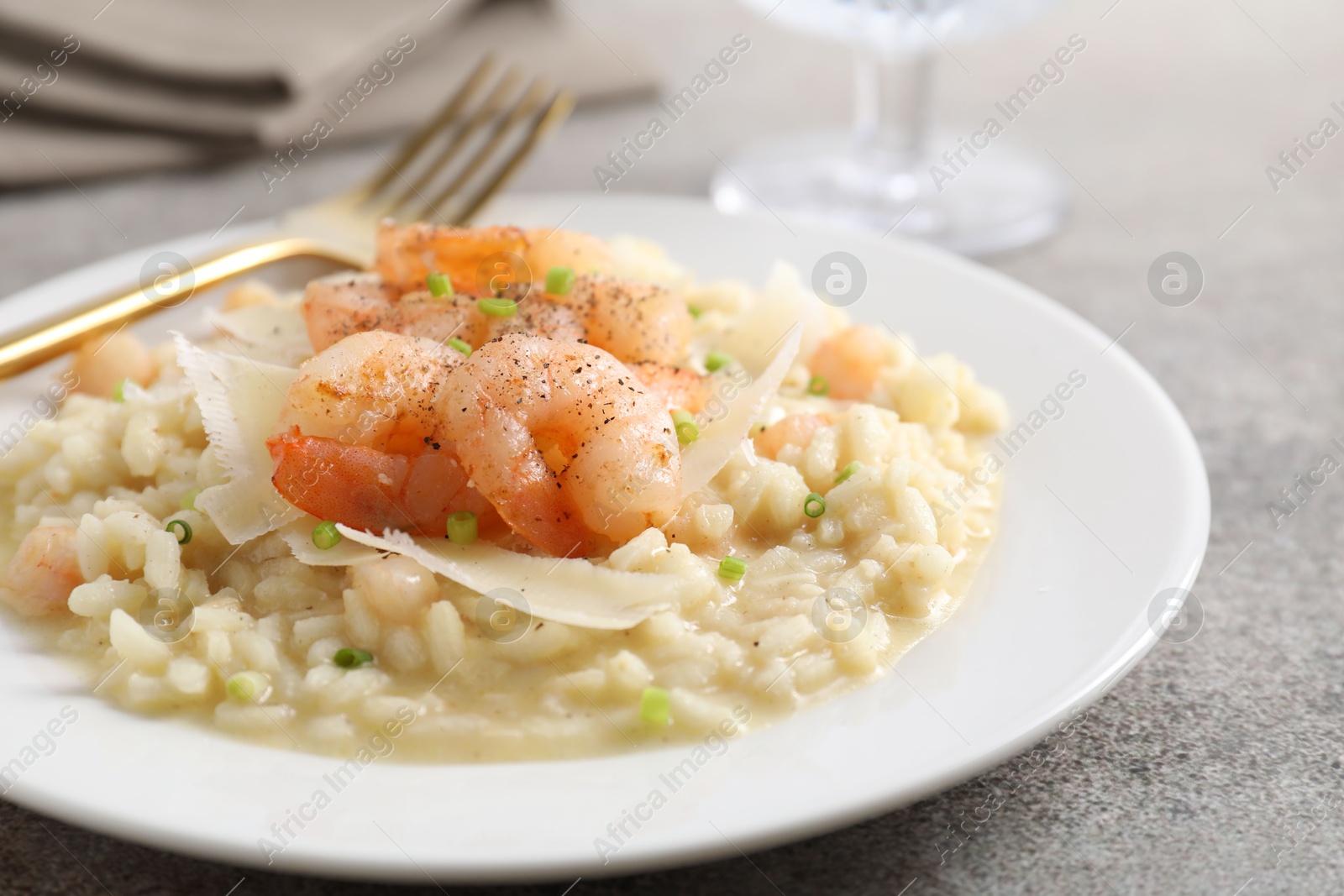 Photo of Delicious risotto with shrimps and cheese on grey table, closeup