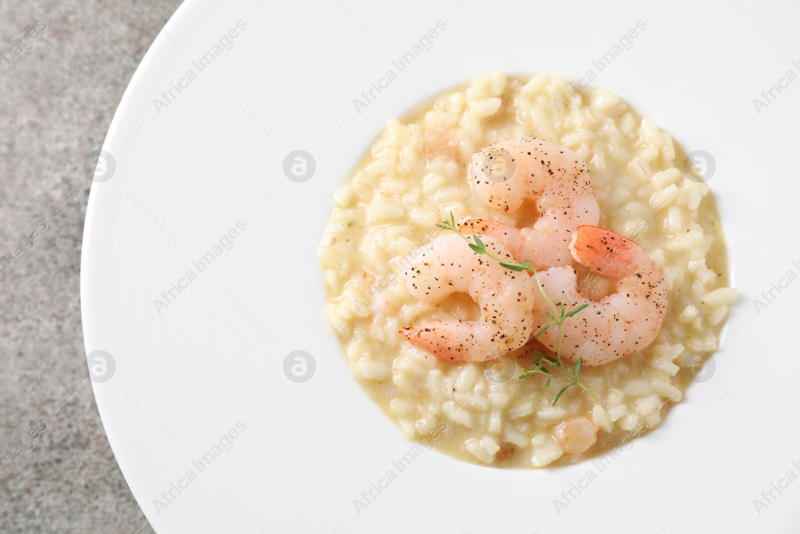 Photo of Delicious risotto with shrimps and cheese on grey table, top view