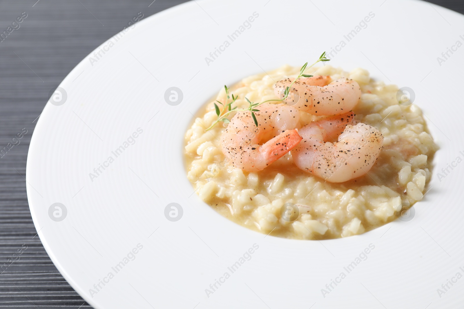 Photo of Delicious risotto with shrimps and cheese on black table