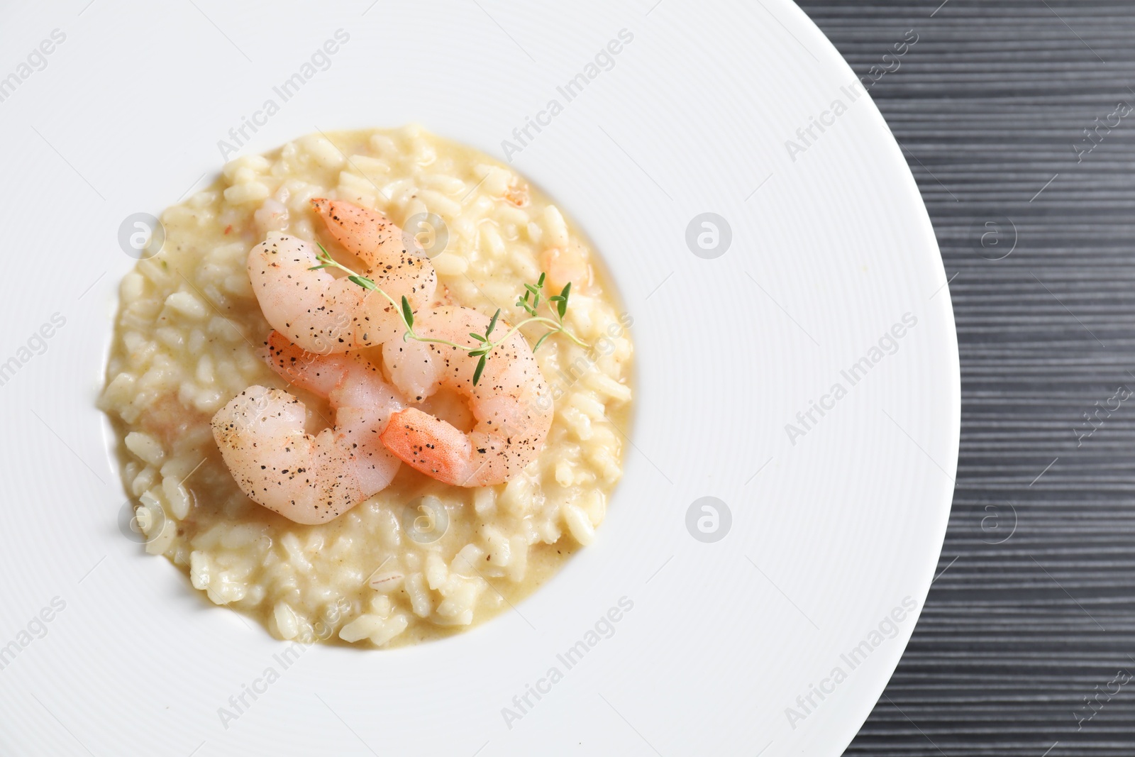 Photo of Delicious risotto with shrimps and cheese on black table, top view