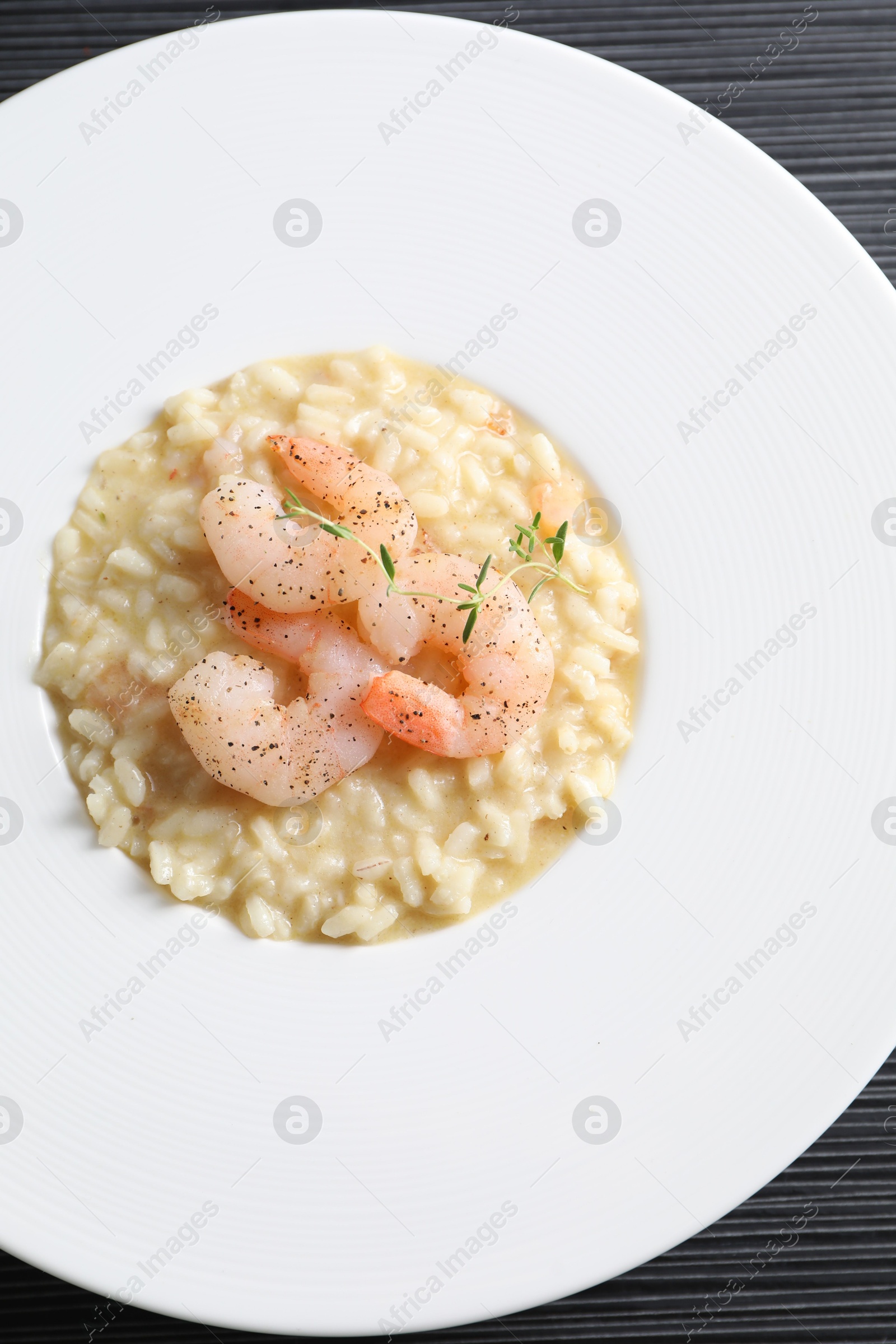 Photo of Delicious risotto with shrimps and cheese on black table, top view