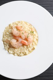 Photo of Delicious risotto with shrimps and cheese on black table, top view