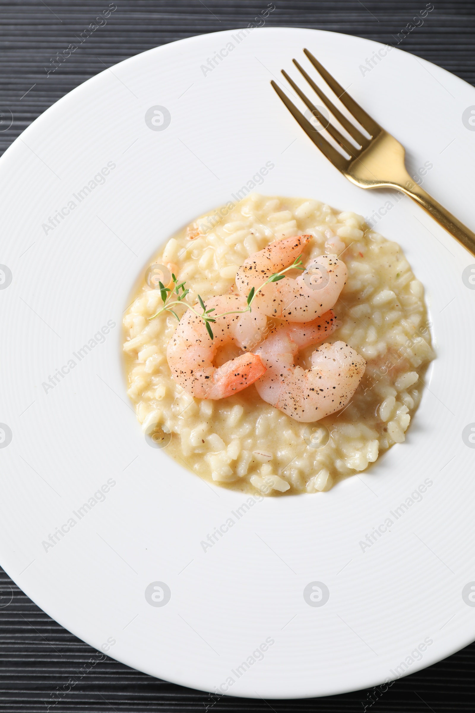 Photo of Delicious risotto with shrimps and cheese on black table, top view