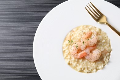 Photo of Delicious risotto with shrimps and cheese on black table, top view