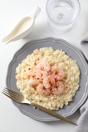 Photo of Delicious risotto with shrimps, cheese, sauce and water on white table, top view