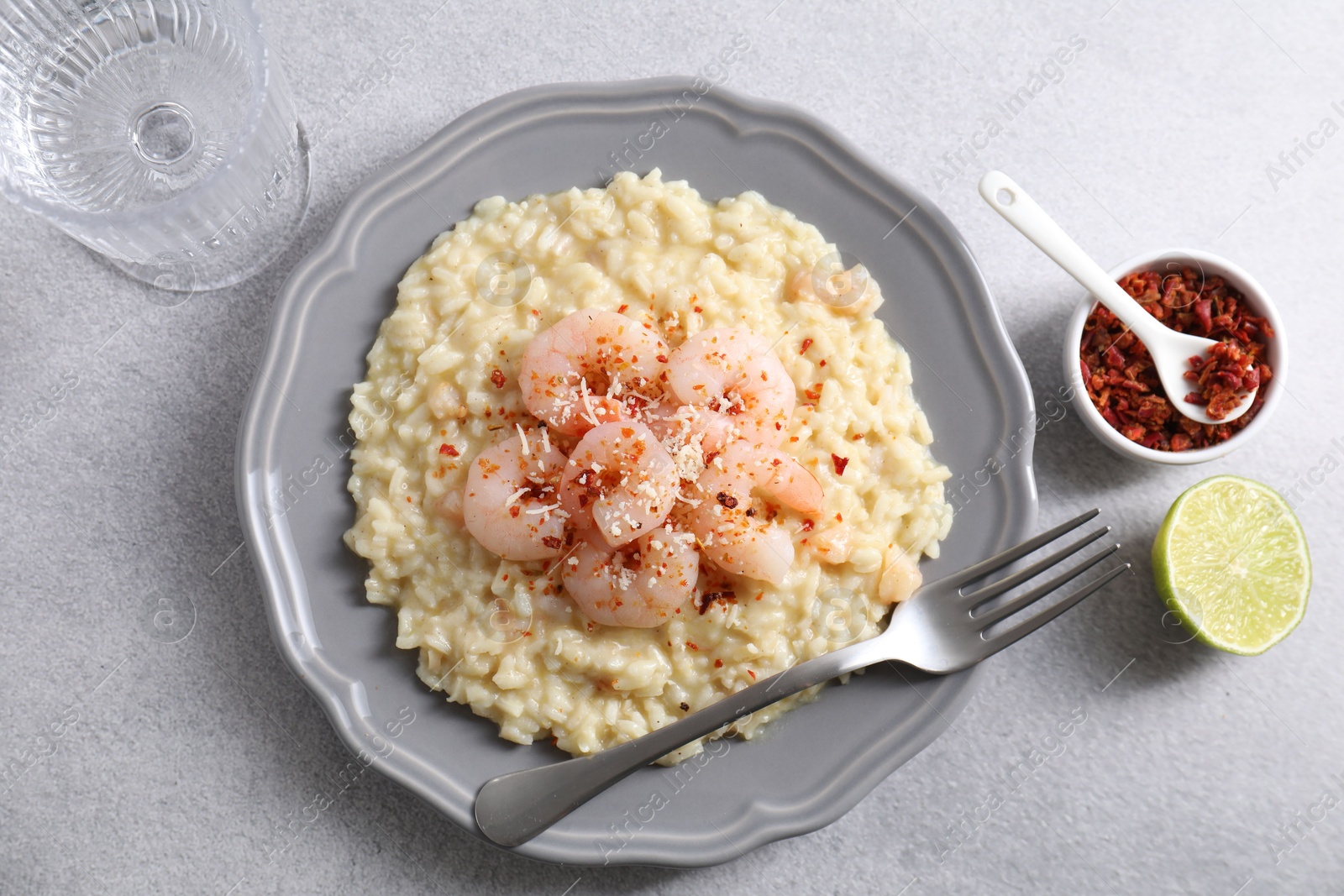 Photo of Delicious risotto with shrimps and cheese served on light grey table, top view