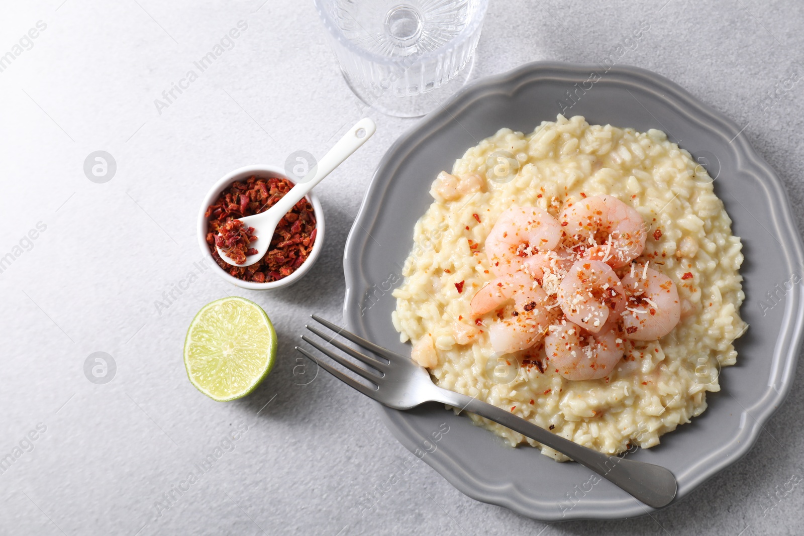 Photo of Delicious risotto with shrimps and cheese served on light grey table, top view