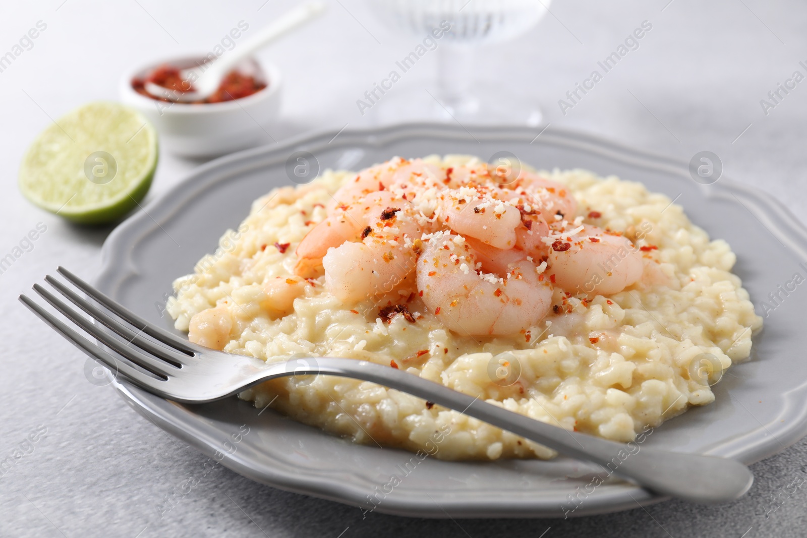 Photo of Delicious risotto with shrimps and cheese on light grey table, closeup