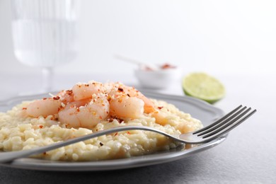 Photo of Delicious risotto with shrimps and cheese on light grey table, closeup