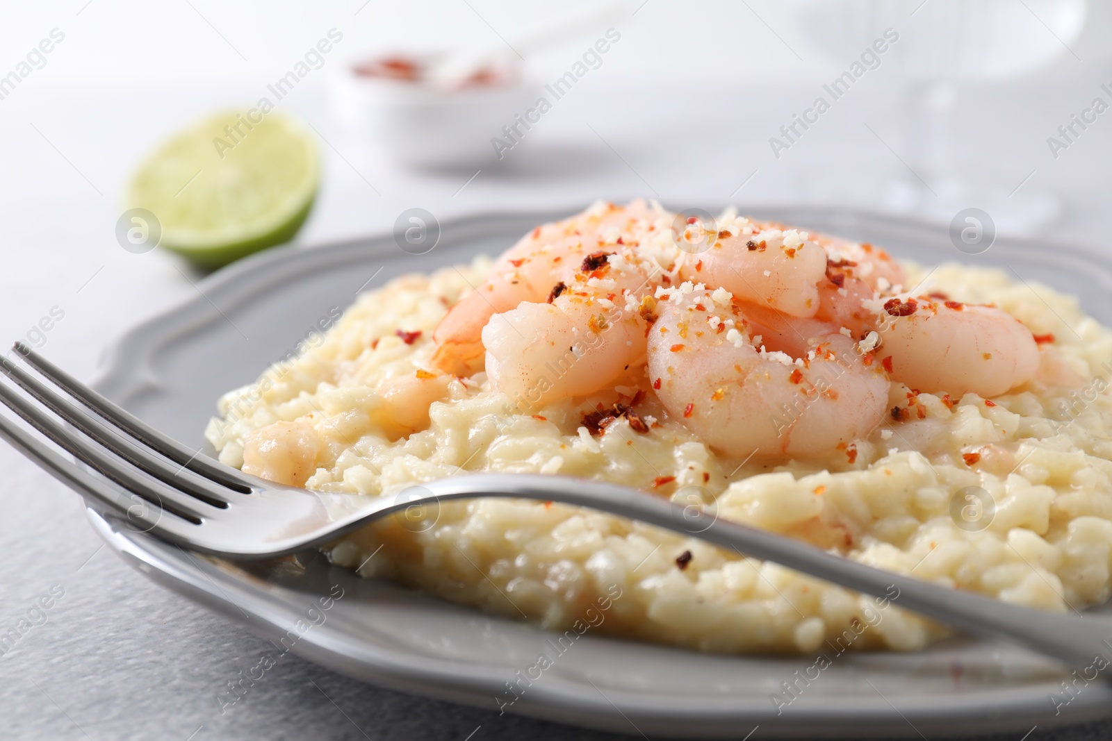 Photo of Delicious risotto with shrimps and cheese on light grey table, closeup