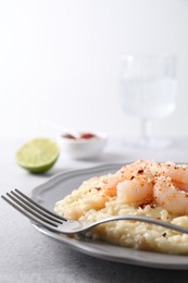 Photo of Delicious risotto with shrimps and cheese on light grey table, closeup