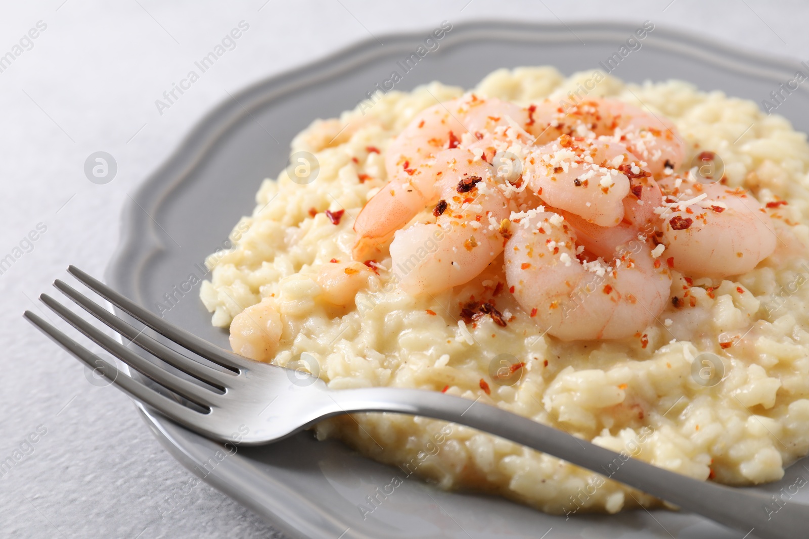 Photo of Delicious risotto with shrimps and cheese on light grey table, closeup