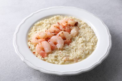 Photo of Delicious risotto with shrimps and cheese on light grey table, closeup