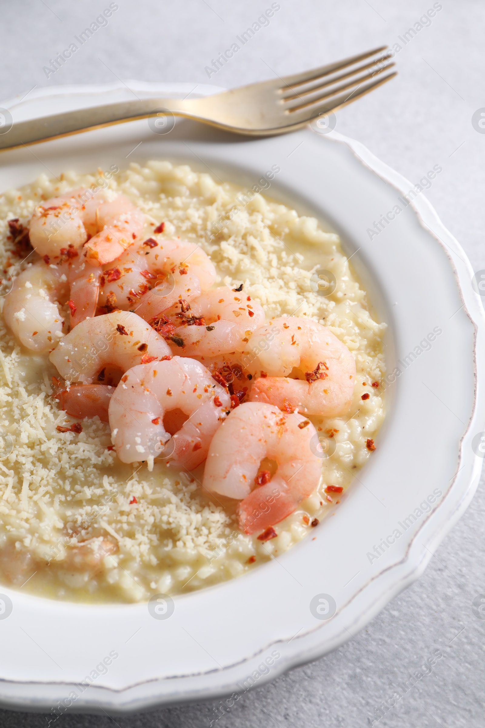 Photo of Delicious risotto with shrimps and cheese on light grey table, closeup