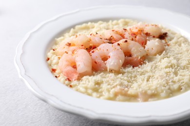 Photo of Delicious risotto with shrimps and cheese on light grey table, closeup