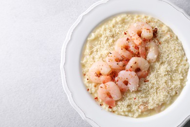 Photo of Delicious risotto with shrimps and cheese on light grey table, top view. Space for text