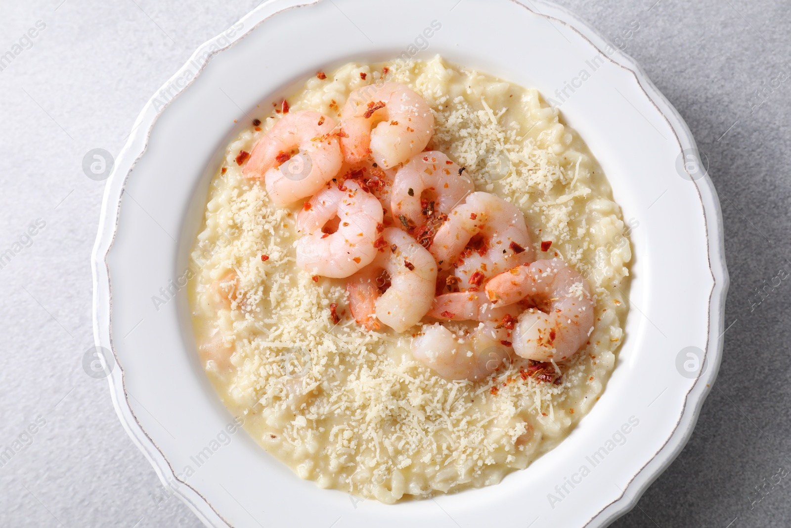 Photo of Delicious risotto with shrimps and cheese on light grey table, top view