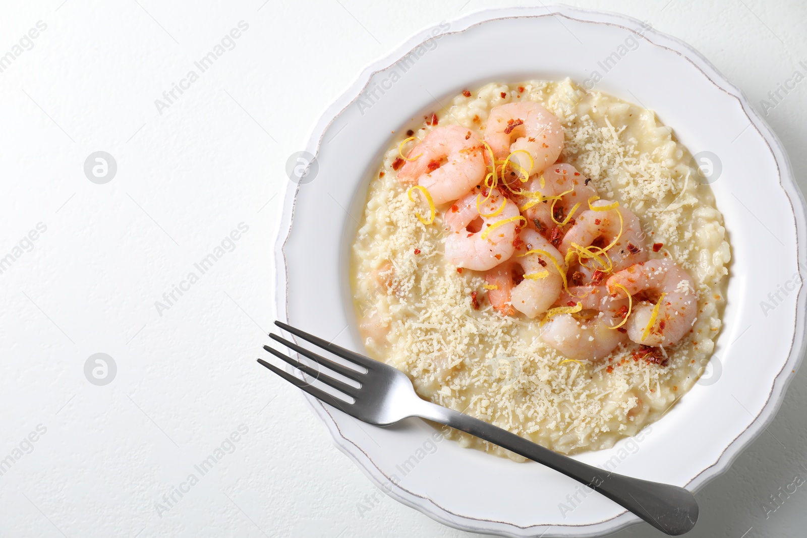 Photo of Delicious risotto with shrimps and cheese on white table, top view. Space for text