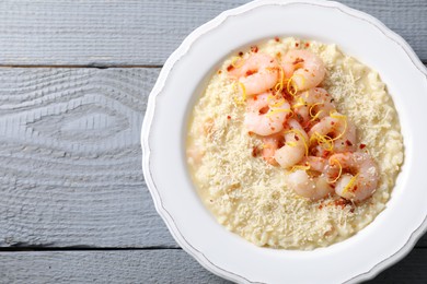 Photo of Delicious risotto with shrimps and cheese on grey wooden table, top view. Space for text