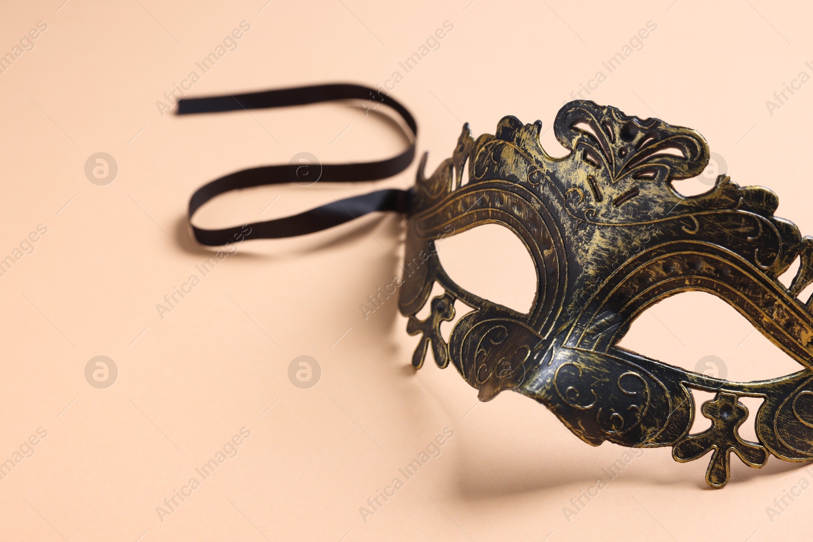 Photo of Beautiful carnival mask on beige background, space for text