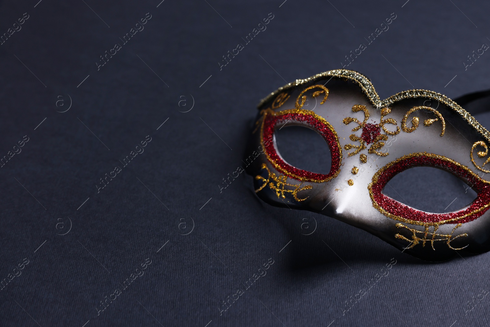 Photo of Beautiful carnival mask on black background, space for text