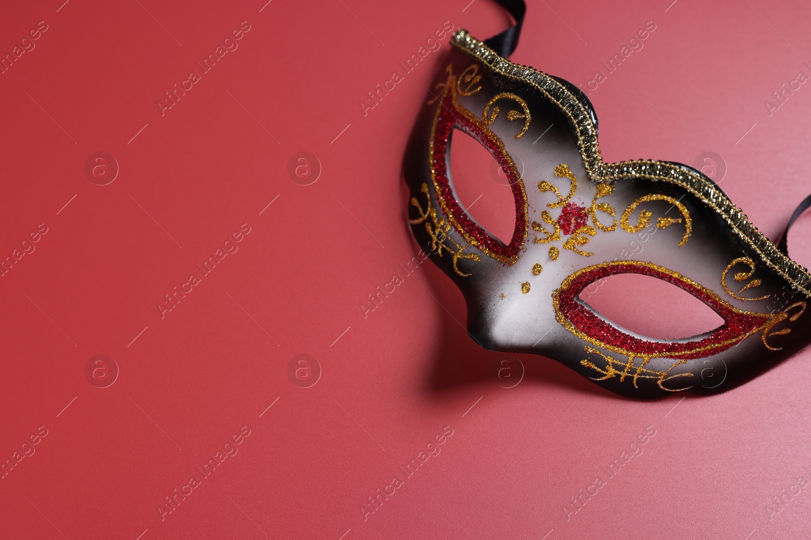 Photo of Beautiful carnival mask on red background, top view. Space for text