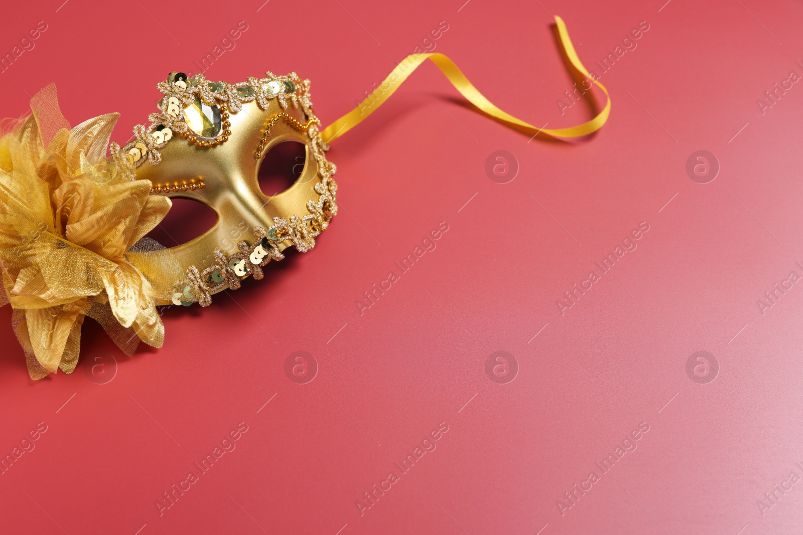 Photo of Beautiful carnival mask on red background, space for text