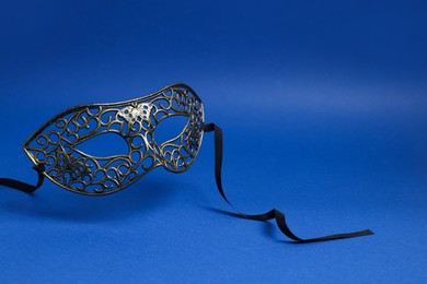 Photo of Beautiful carnival mask in air on blue background