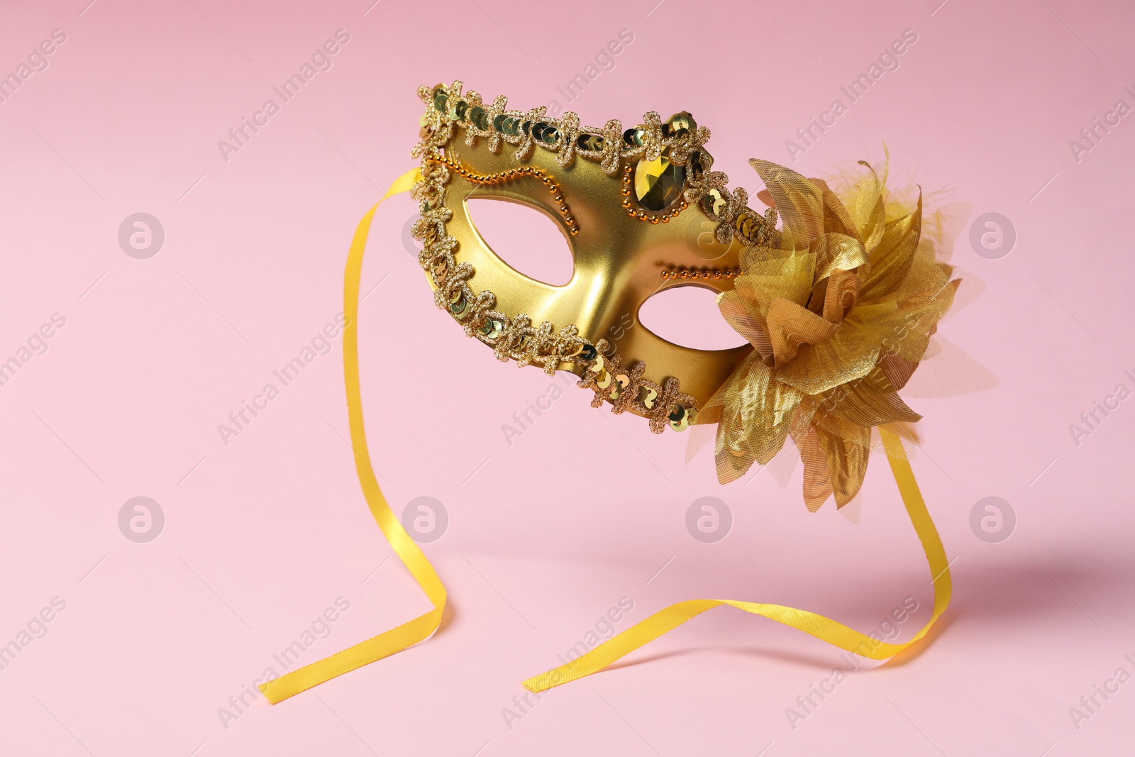 Photo of Beautiful carnival mask in air on pink background