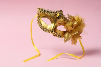 Photo of Beautiful carnival mask in air on pink background