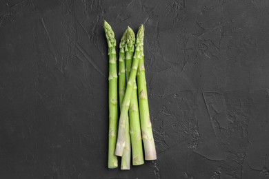 Photo of Fresh green asparagus stems on gray textured table, top view