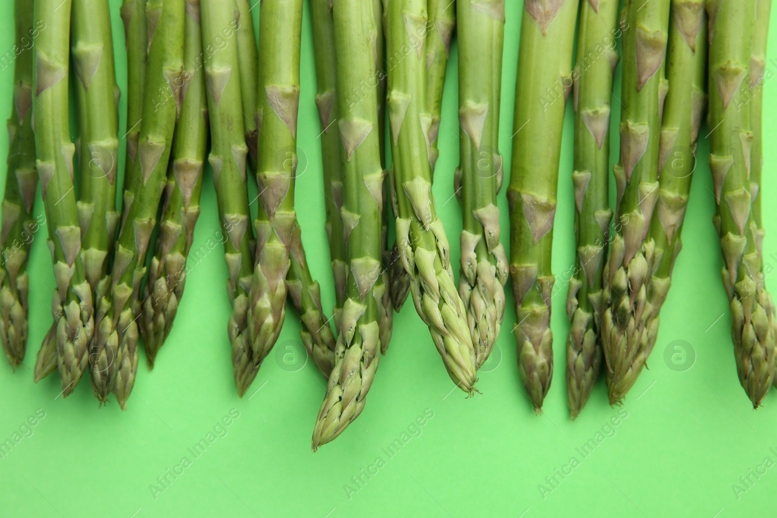 Photo of Fresh asparagus stems on green table, top view