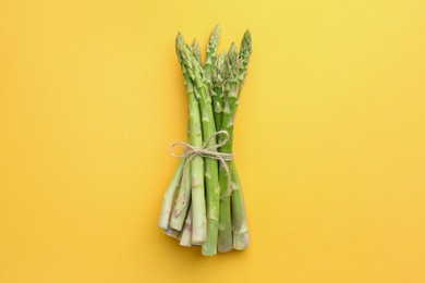 Fresh green asparagus stems on orange table, top view