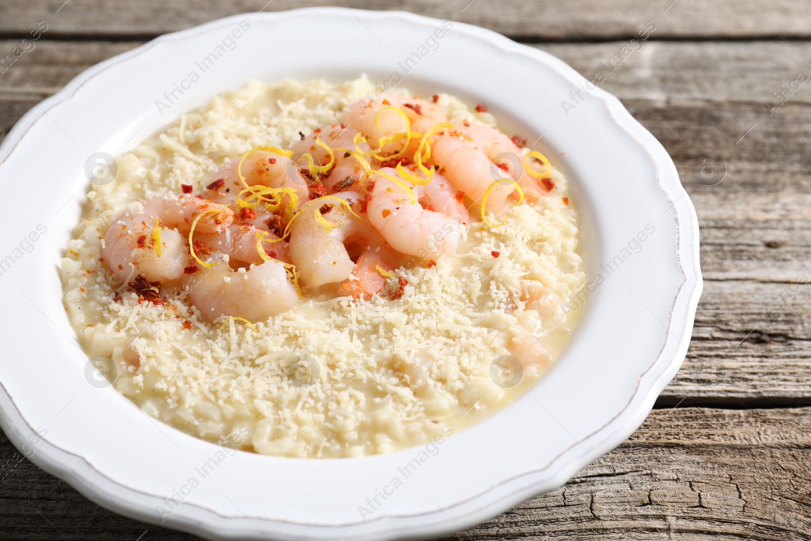 Photo of Delicious risotto with shrimps and cheese on wooden table, closeup