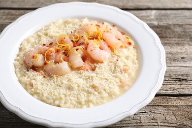 Photo of Delicious risotto with shrimps and cheese on wooden table, closeup