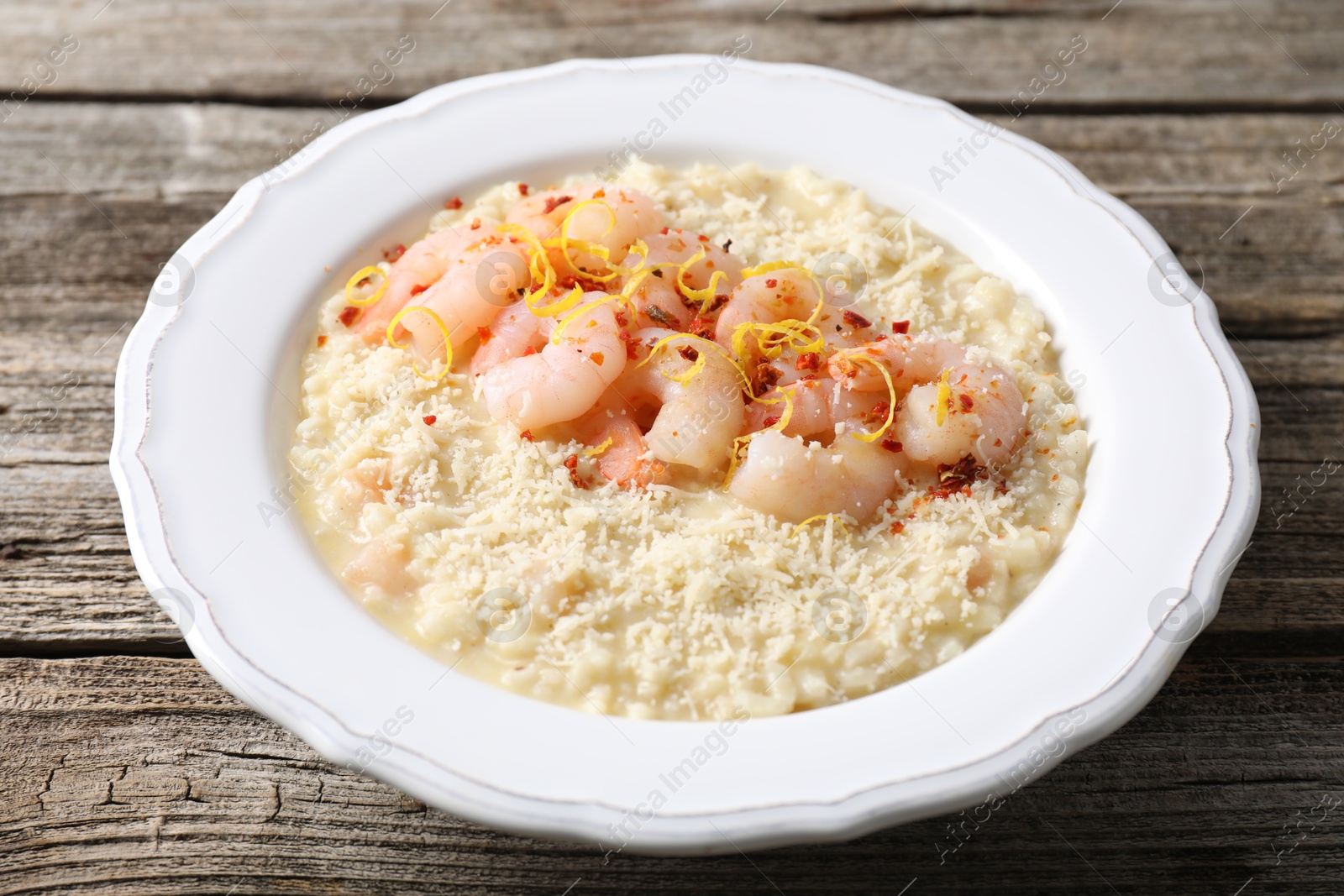 Photo of Delicious risotto with shrimps and cheese on wooden table, closeup