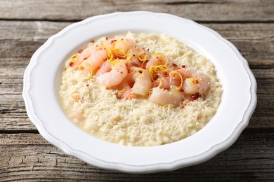 Photo of Delicious risotto with shrimps and cheese on wooden table, closeup