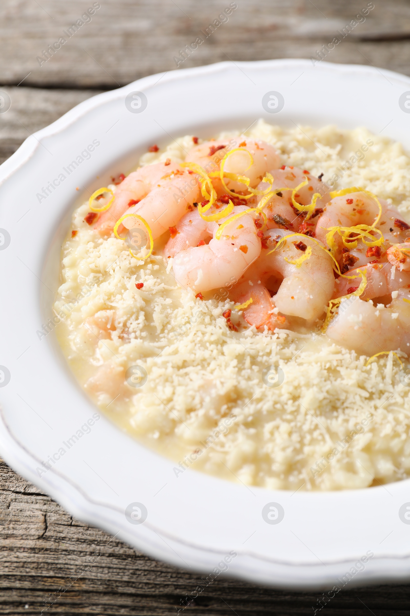 Photo of Delicious risotto with shrimps and cheese on wooden table, closeup