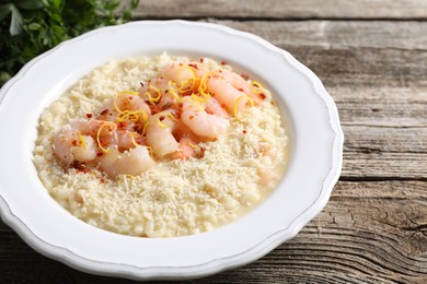 Photo of Delicious risotto with shrimps and cheese on wooden table, closeup