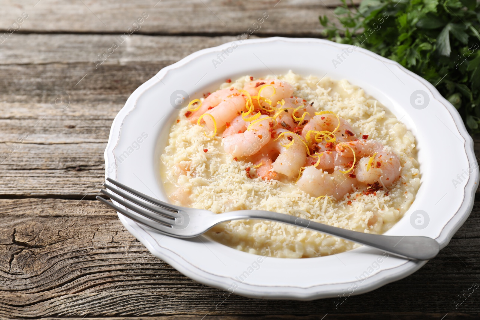 Photo of Delicious risotto with shrimps and cheese on wooden table, closeup