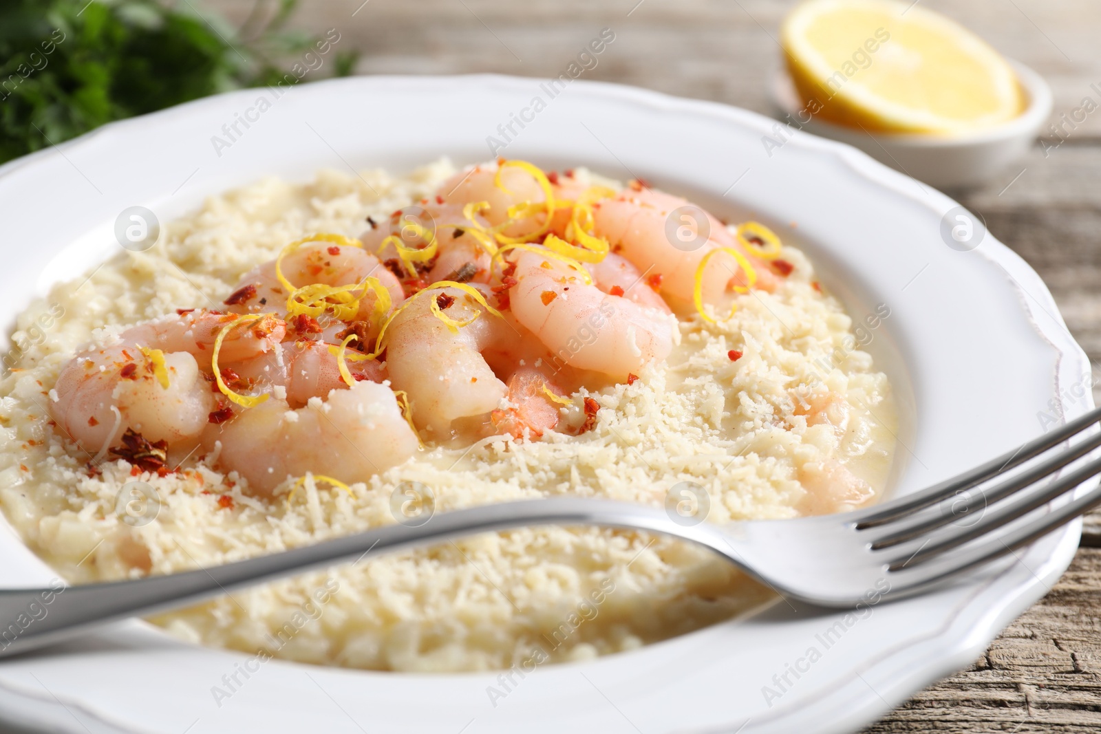 Photo of Delicious risotto with shrimps and cheese on wooden table, closeup