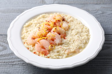 Photo of Delicious risotto with shrimps and cheese on grey wooden table, closeup