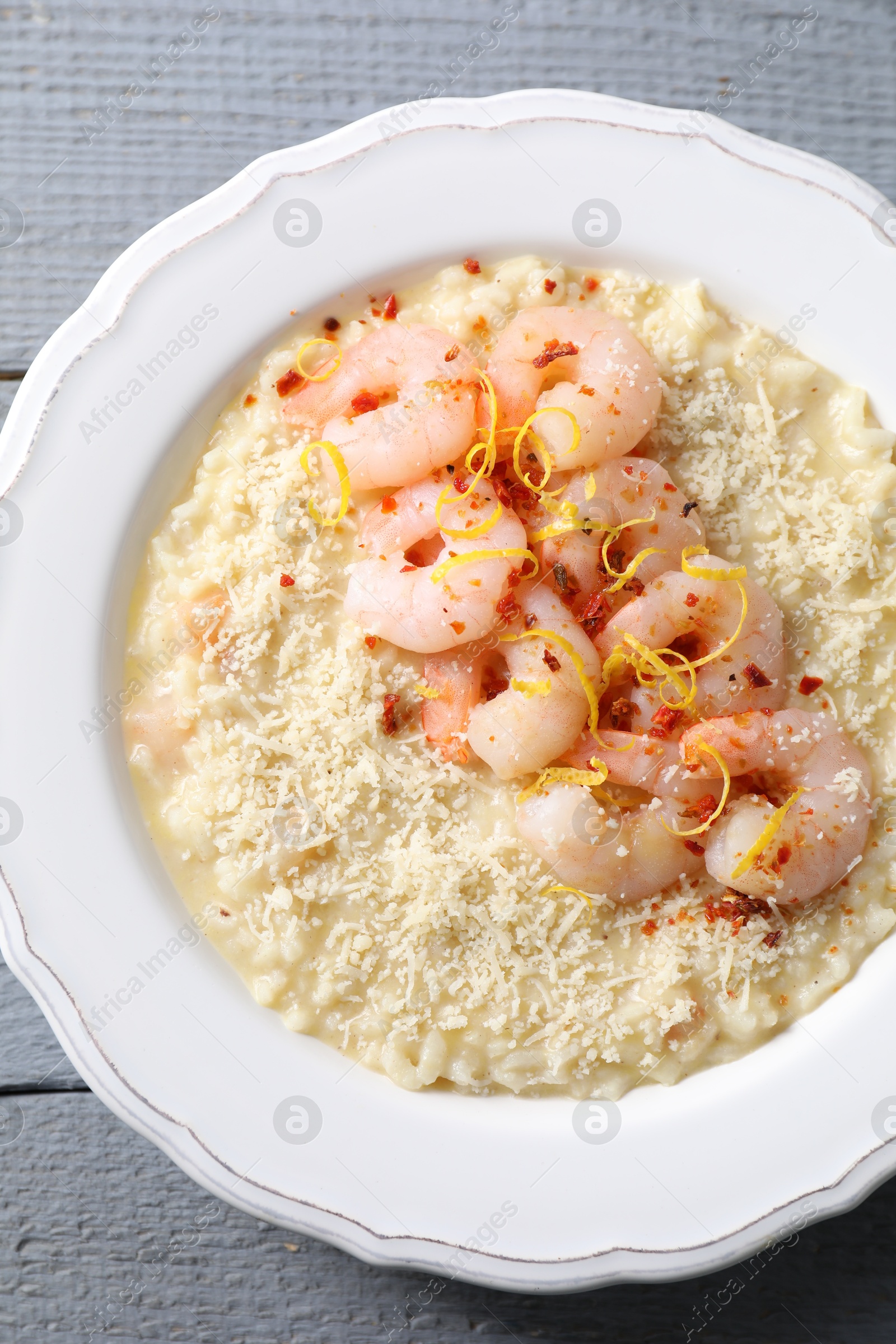 Photo of Delicious risotto with shrimps and cheese on grey wooden table, top view